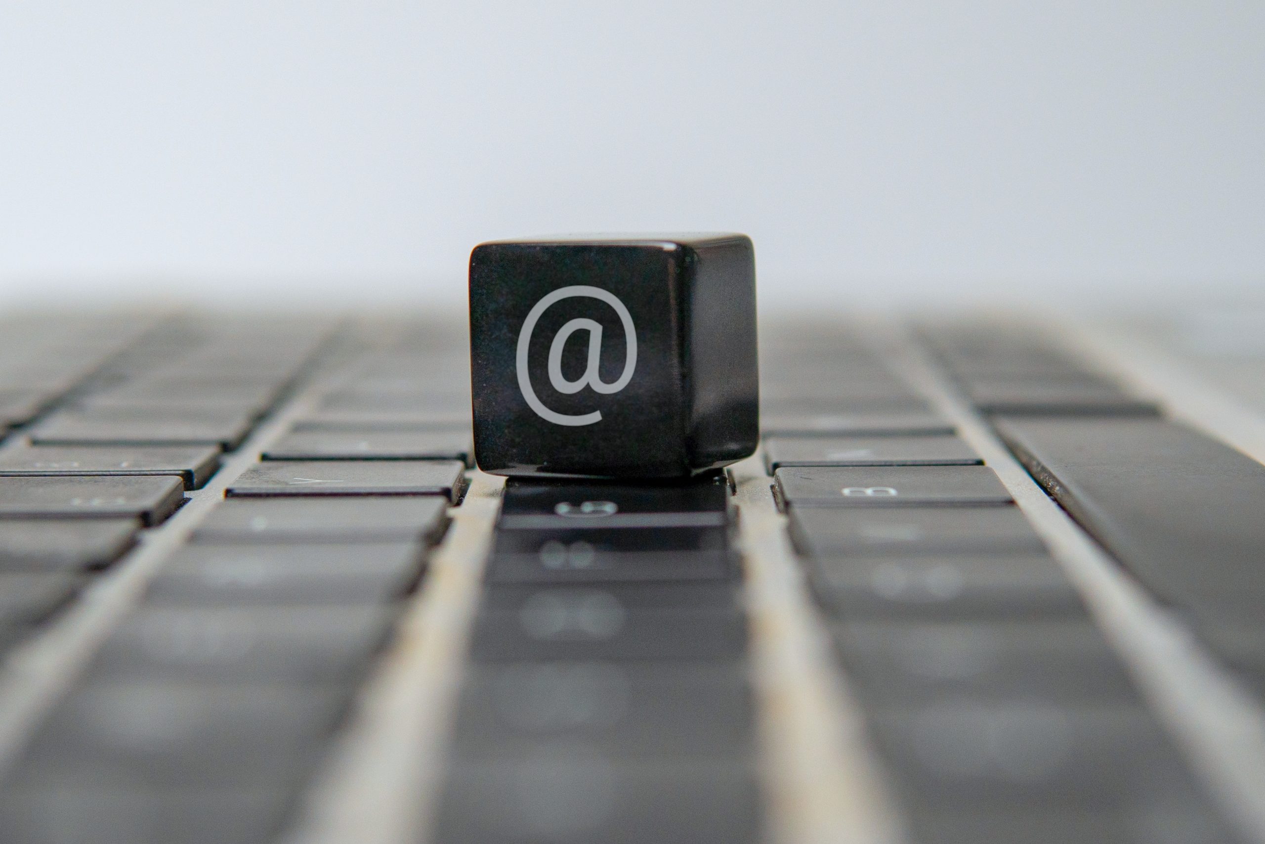 A cube with an at sign or at symbol on a laptop keyboard. Email, internet, communication concept.