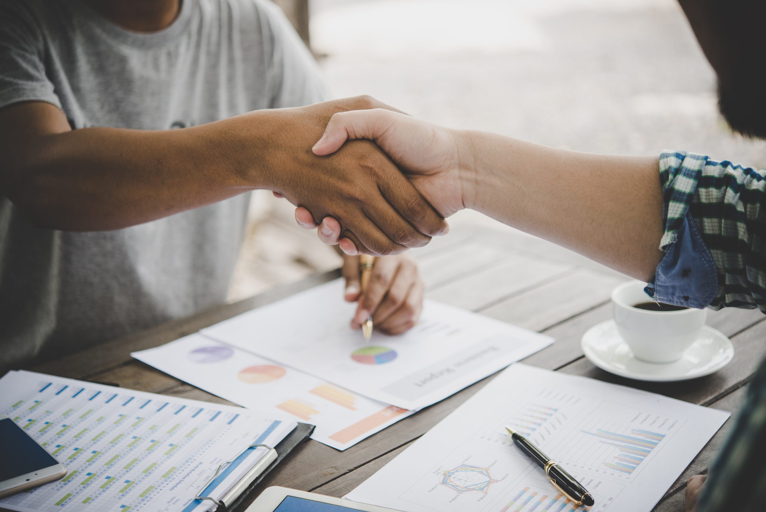 Close-up of two business people shaking hands while sitting at the working place.