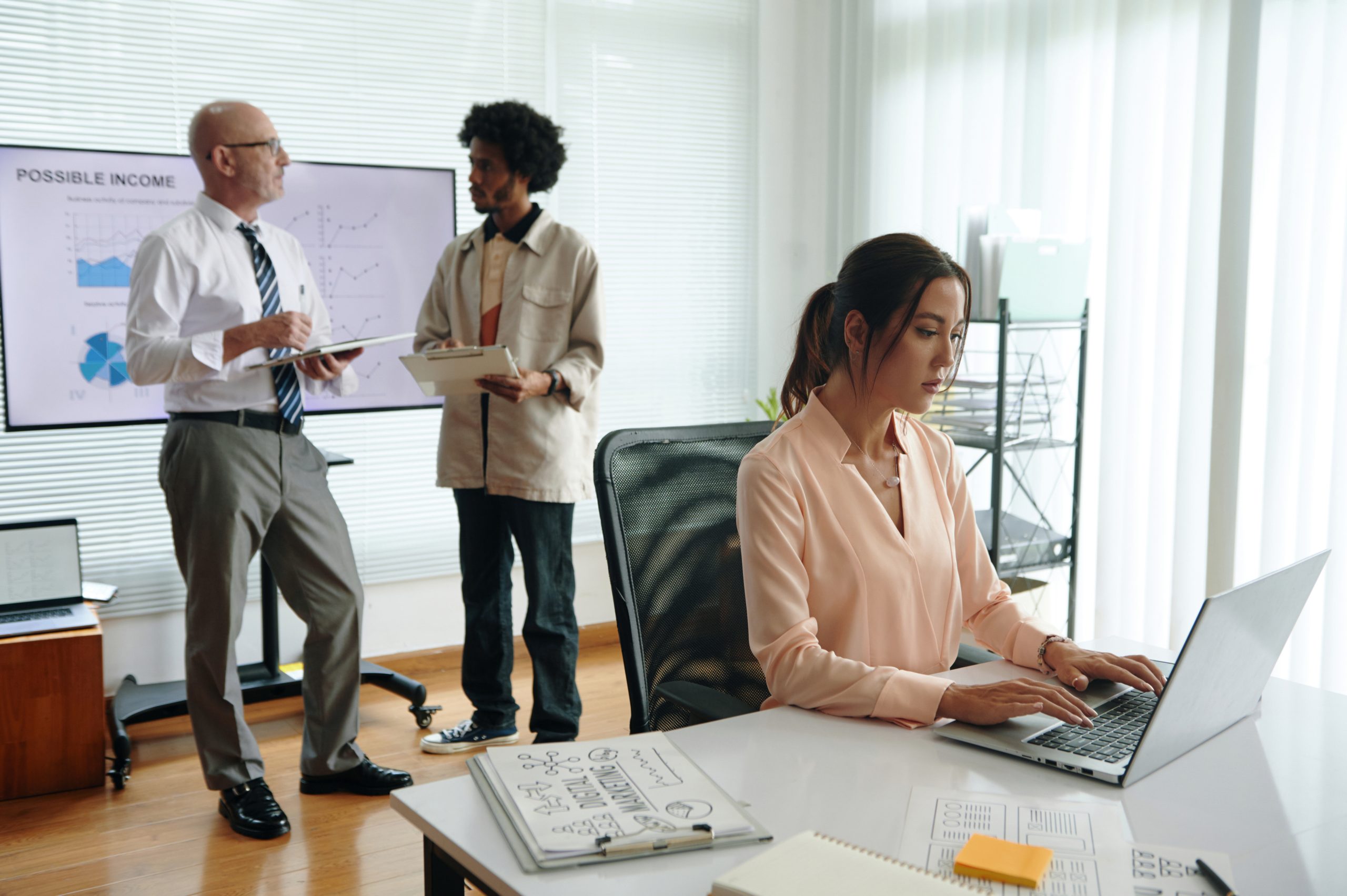 Equipo colaborando con computadoras y documentos en oficina